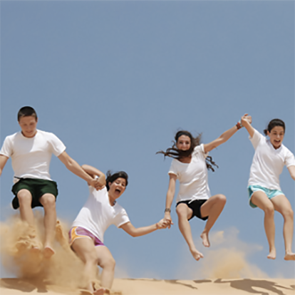 Teens jumping on a dune in Israel