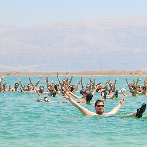 People floating in the Dead Sea with their arms up